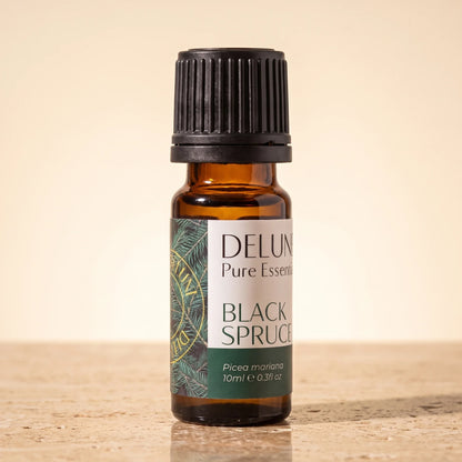 Delune Sortgran – ren æterisk olie, 10 ml ravfarvet glasflaske på varm travertin