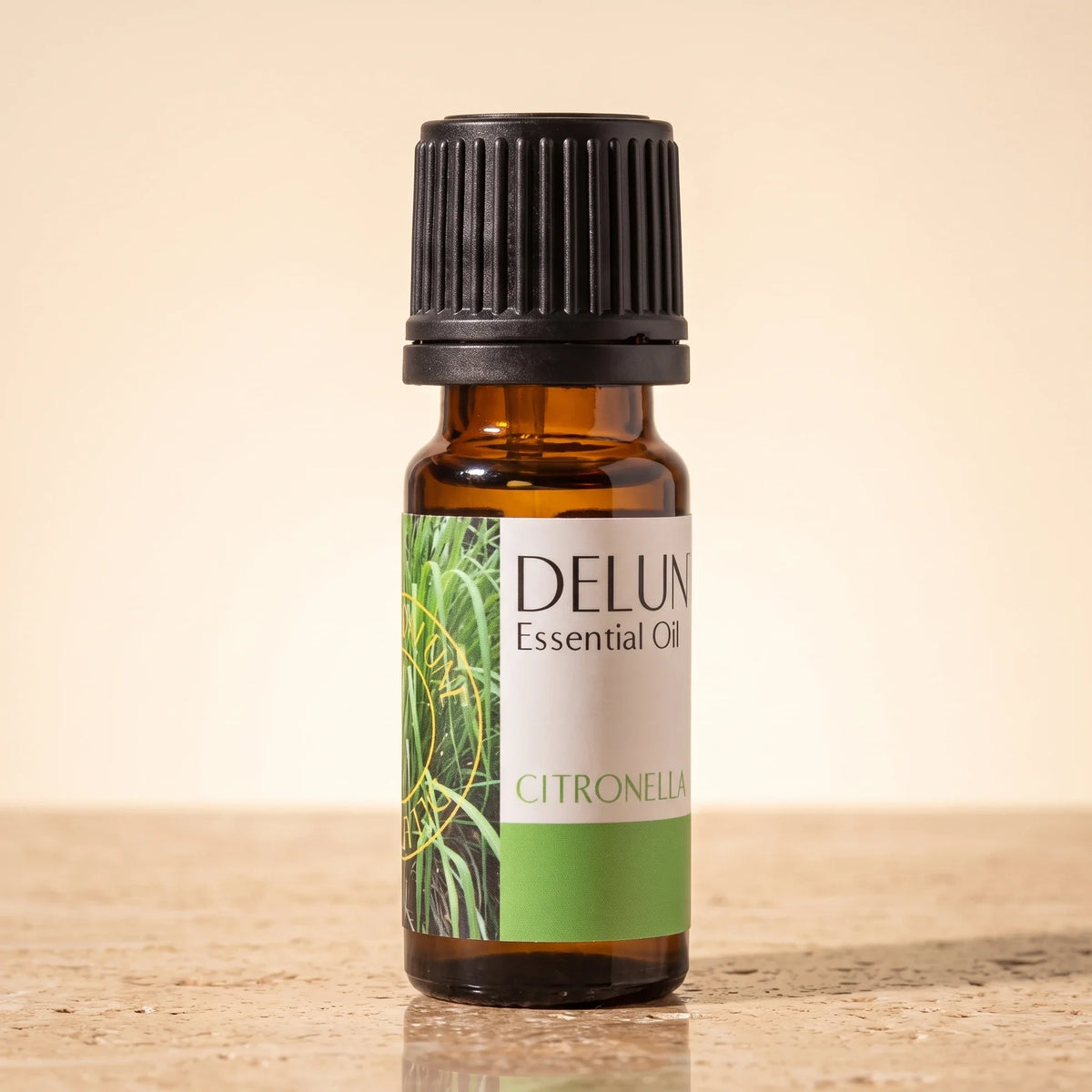 Delune Citronella – ren æterisk olie, 10 ml ravfarvet glasflaske på varm travertin