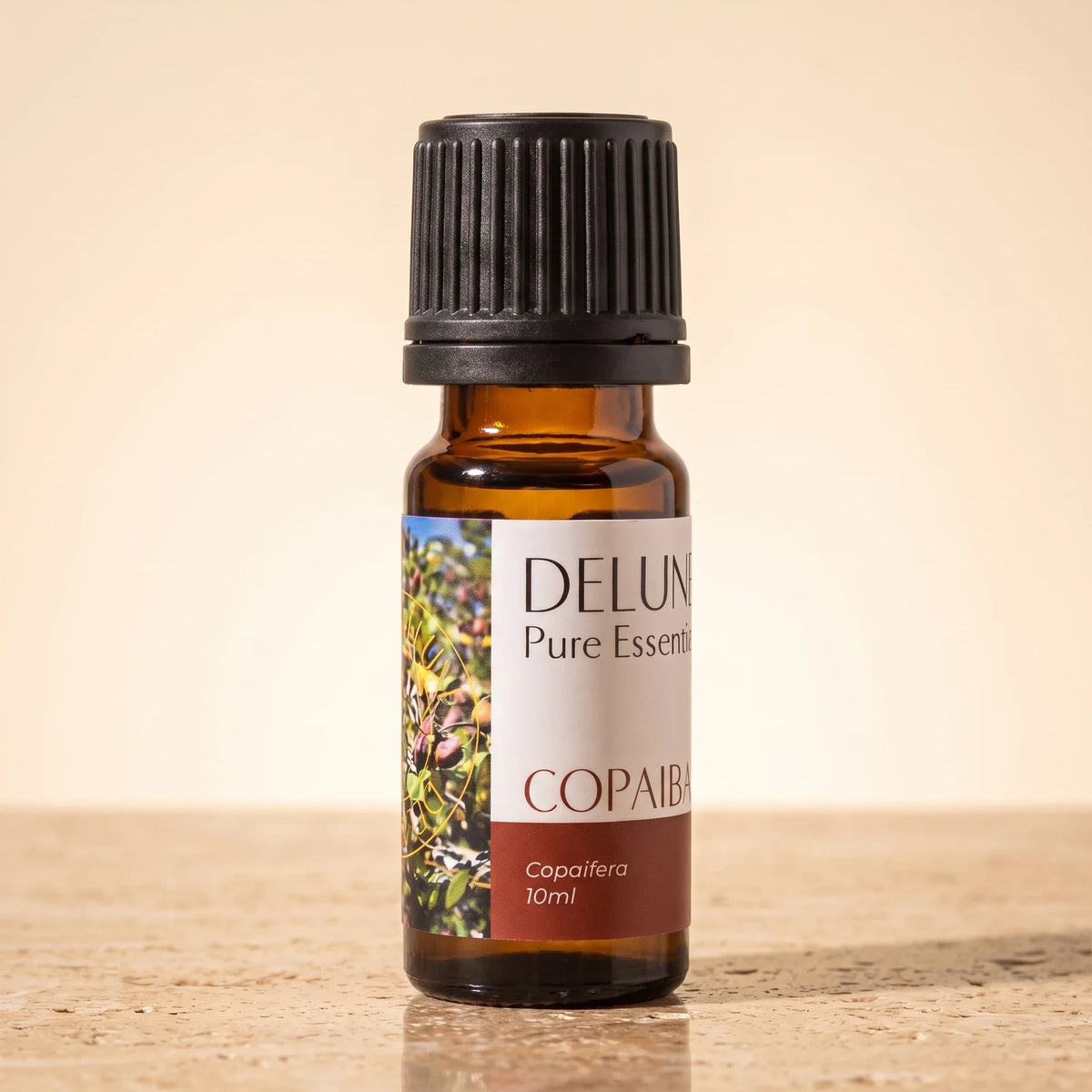 Delune Copaiba – ren æterisk olie, 10 ml ravfarvet glasflaske på varm travertin