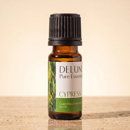 Delune Cypres – ren æterisk olie, 10 ml ravfarvet glasflaske på varm travertin
