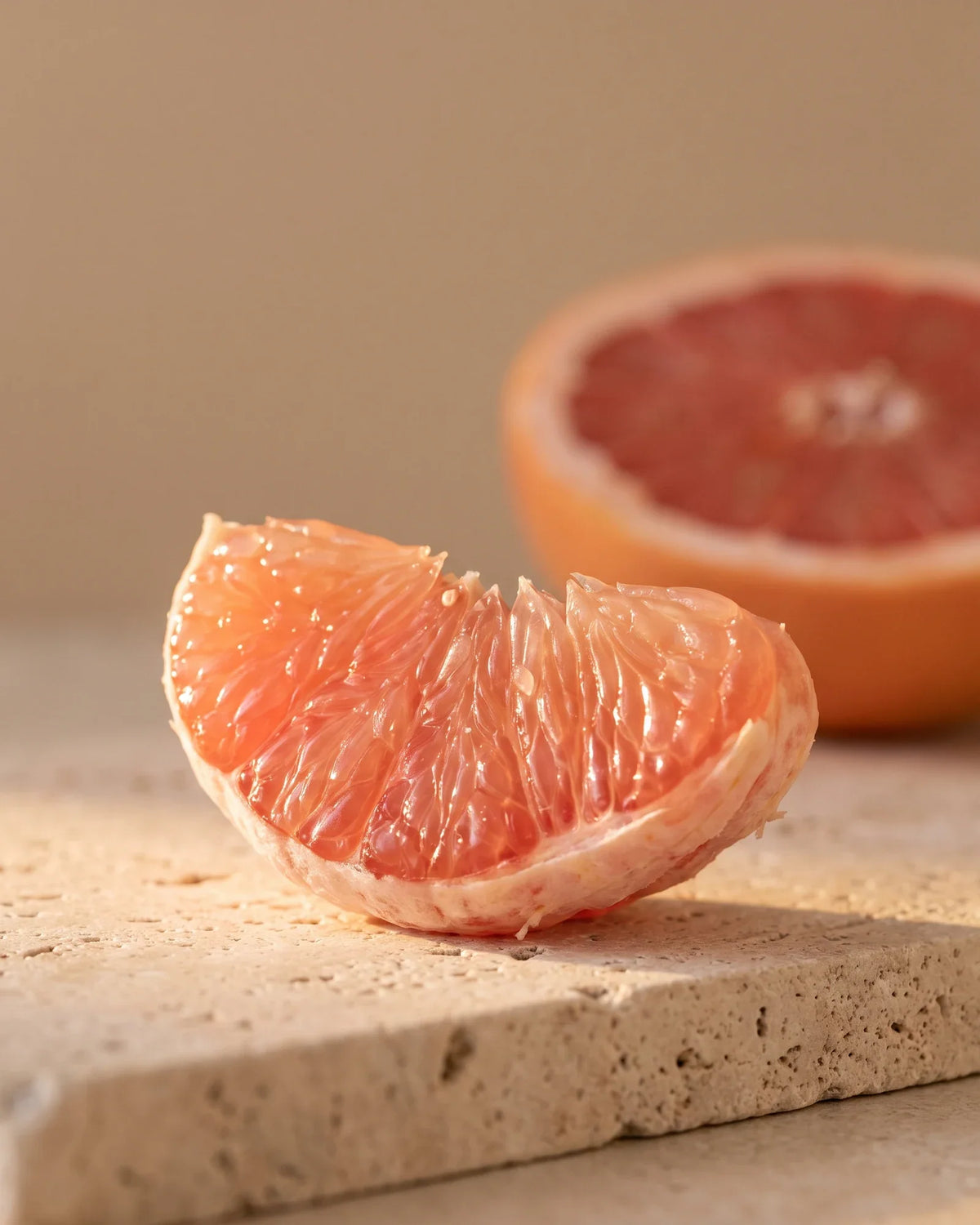 En skinnende båd af lyserød grapefrugt i varmt modlys – den bittersøde, saftige duft fra Delune Lyserød grapefrugt – ren æterisk olie