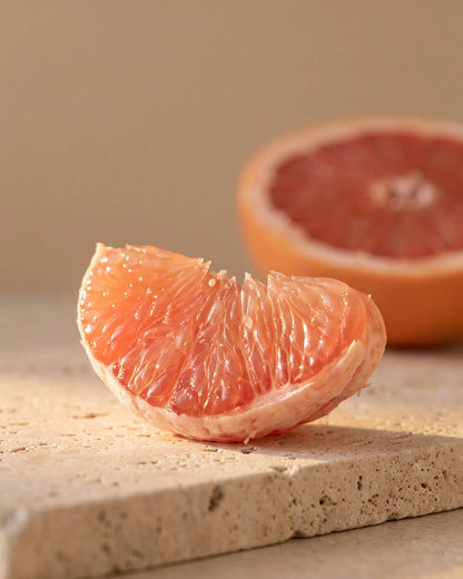 En skinnende båd af lyserød grapefrugt i varmt modlys – den bittersøde, saftige duft fra Delune Lyserød grapefrugt – ren æterisk olie