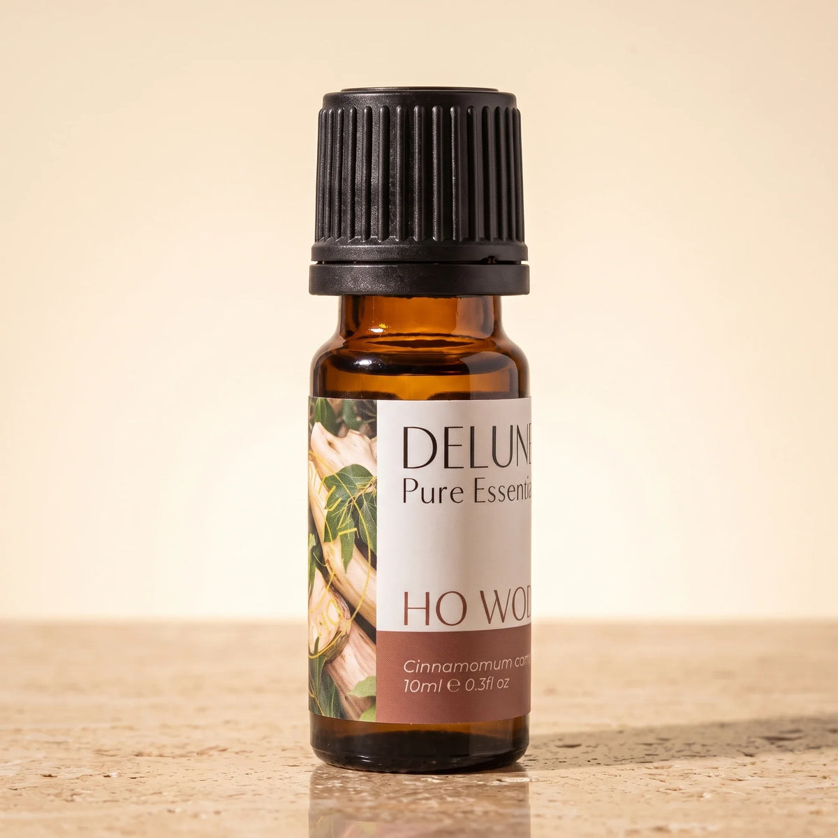 Delune Ho-træ – ren æterisk olie, 10 ml ravfarvet glasflaske på varm travertin