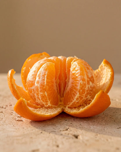En nyskrællet mandarin med både, der gløder i varmt lys – den søde, saftige citrusduft fra Delune Mandarin – ren æterisk olie