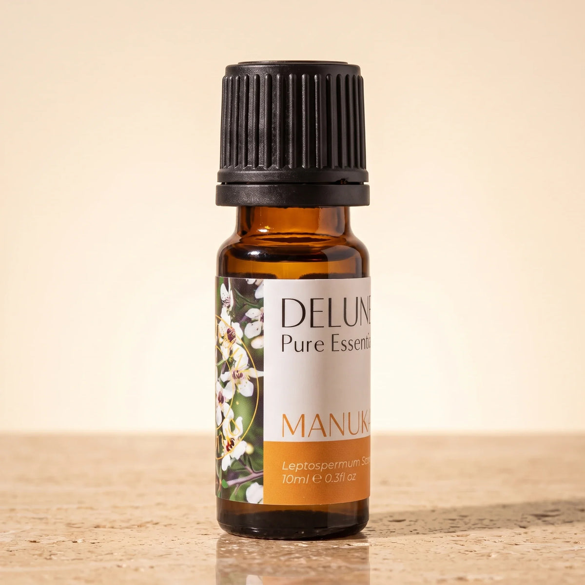 Delune Mānuka – ren æterisk olie, 10 ml ravfarvet glasflaske på varm travertin