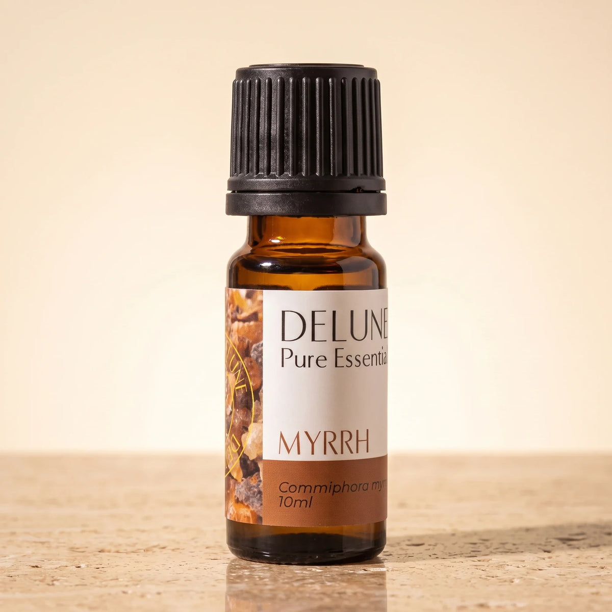 Delune Myrra – ren æterisk olie, 10 ml ravfarvet glasflaske på varm travertin