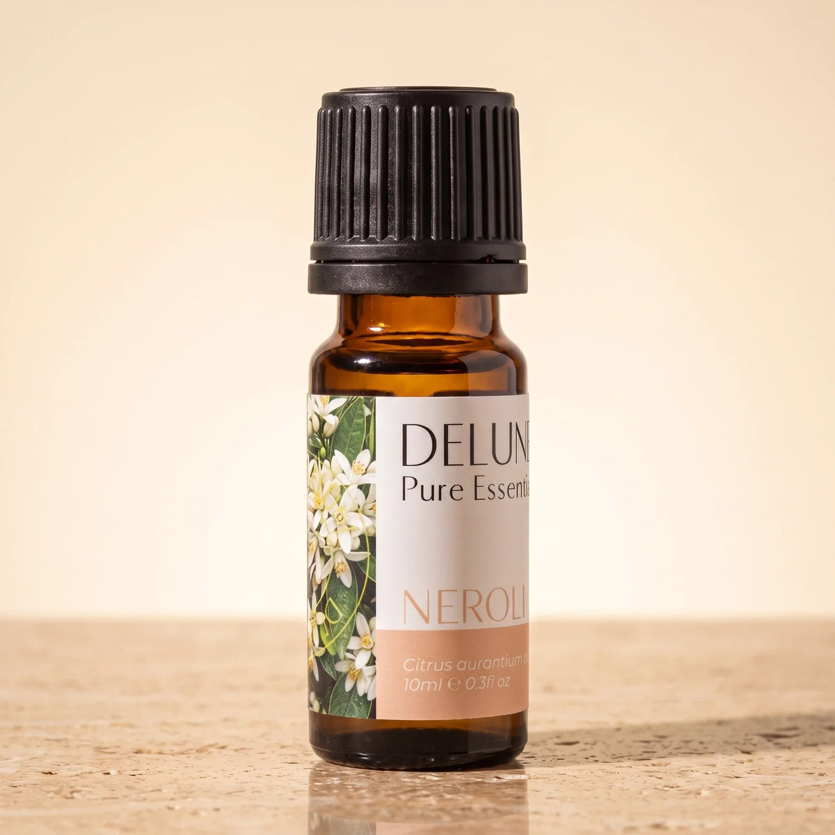 Delune Neroli – ren æterisk olie, 10 ml ravfarvet glasflaske på varm travertin