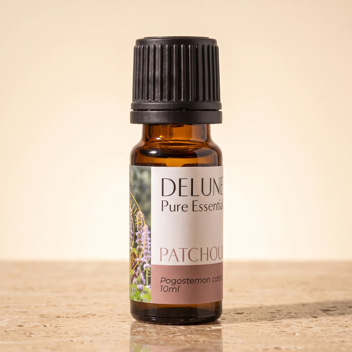 Delune Patchouli – ren æterisk olie, 10 ml ravfarvet glasflaske på varm travertin