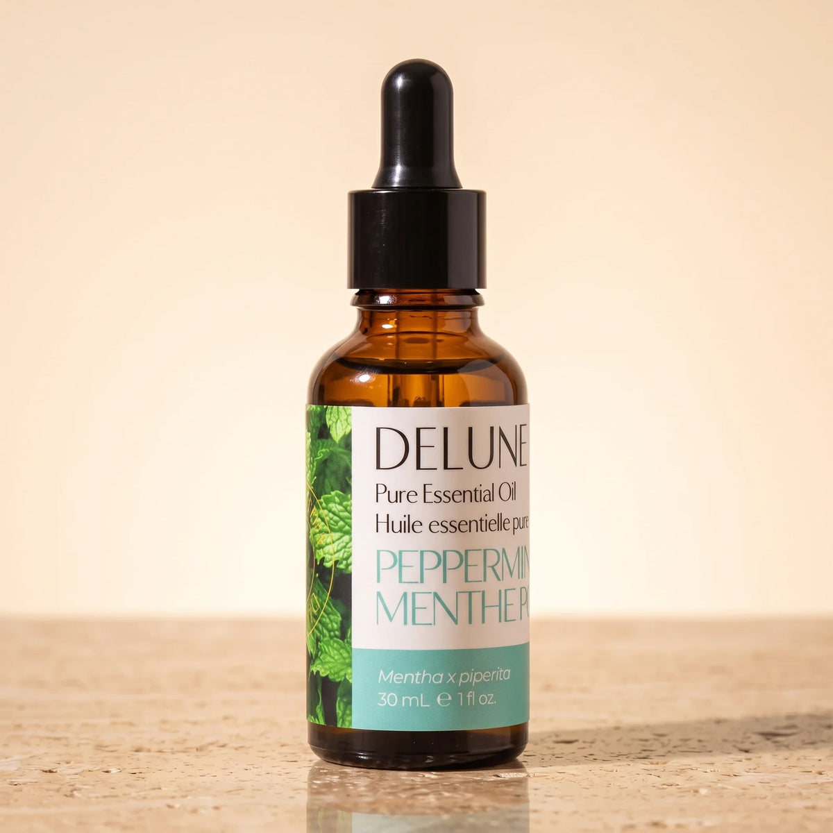 Delune Pebermynte – ren æterisk olie, 30 ml ravfarvet pipetteflaske på varm travertin