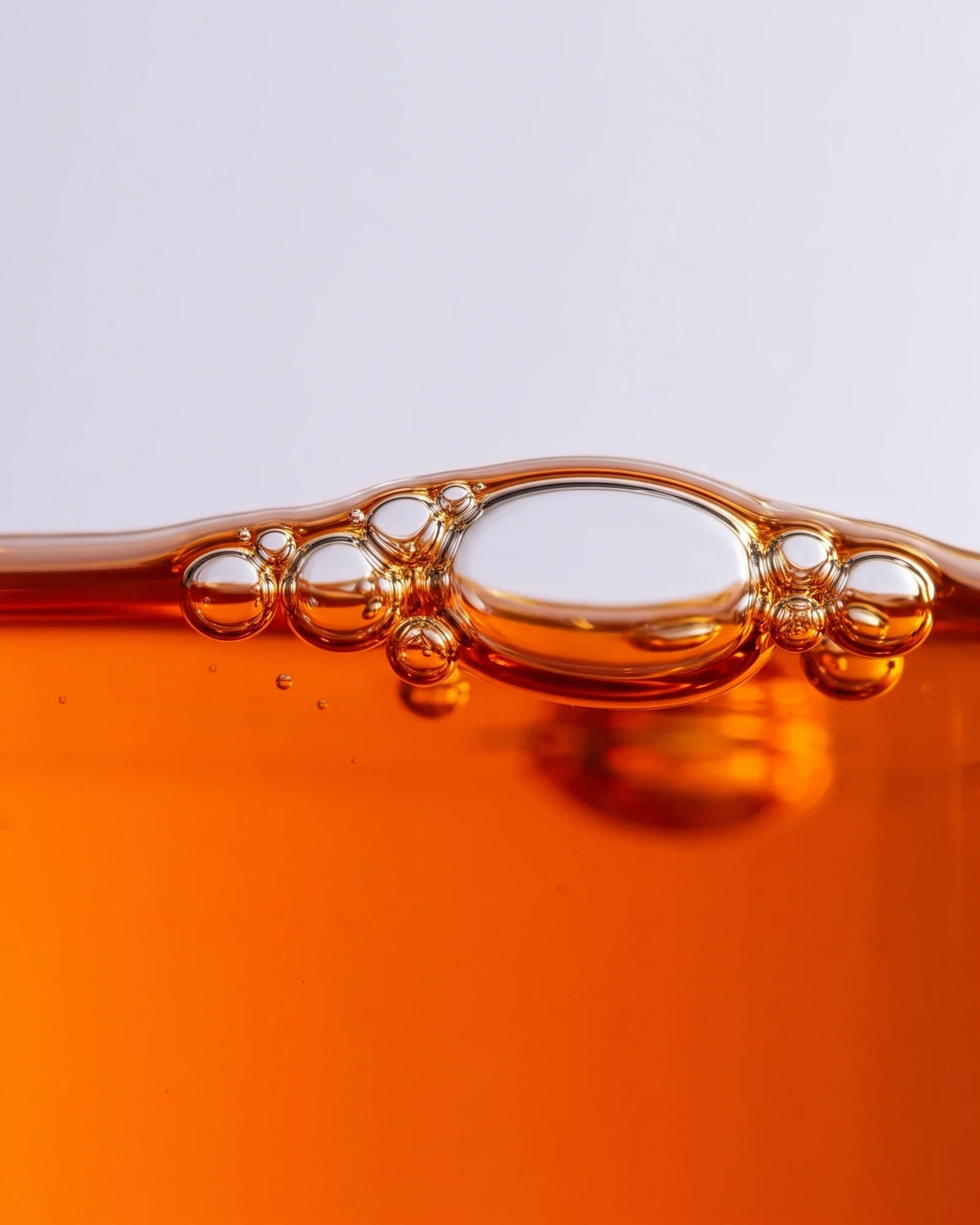 Teksturen i Revive 49 % havtornolieserum: nærbillede af klar orange havtornolie med bobler i overfladen