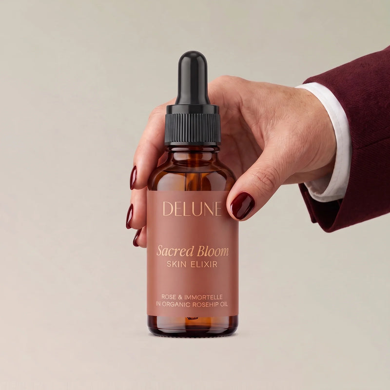 Hånd, der holder Sacred Bloom Skin Elixir – ansigtsolie fra Delune