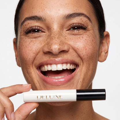 Delune Tubing Mascara, model laughing with lifted lashes, holding the white tube