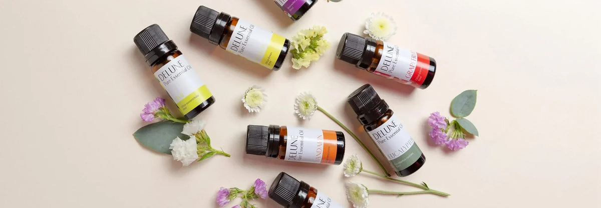 Delunes flasker med æteriske olier lagt frem med friske blomster og eukalyptus