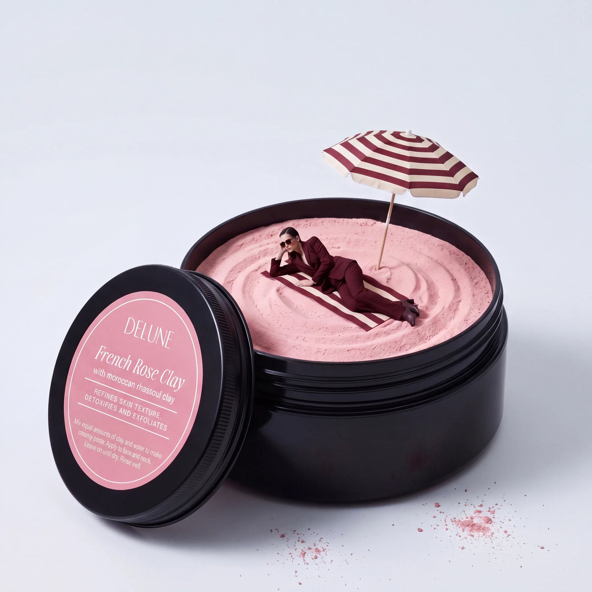 Ritual: en kvinde i oxblodsrødt jakkesæt slapper af under en parasol på lyserødt ler i en kæmpe krukke Delune French Rose Clay
